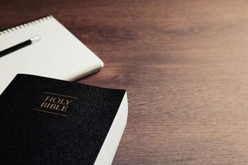 Holy Bible and notebook with pencil on wooden table, closeup. Space for text. Religious book