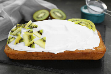 Delicious homemade yogurt cake with kiwi and cream on gray table, closeup