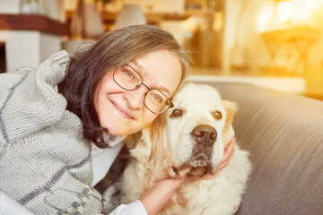 Alte Frau als Seniorin streichelt und kuschelt mit Hund