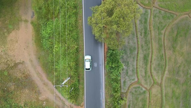 Top Down shot of a car traveling down a wet back country road in Mahiyangana
