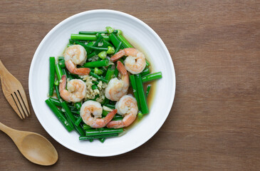 top view of stir fried shrimp with onion flower stem in a ceramic dish on wooden table. asian homemade style food concept.