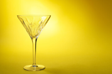 Elegant empty martini glass on yellow background. Space for text