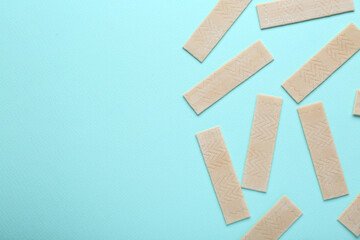 Many sticks of tasty chewing gum on light blue background, flat lay. Space for text