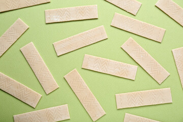 Many sticks of tasty chewing gum on light green background, flat lay
