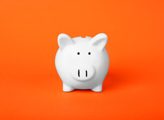 Ceramic piggy bank on orange background. Financial savings