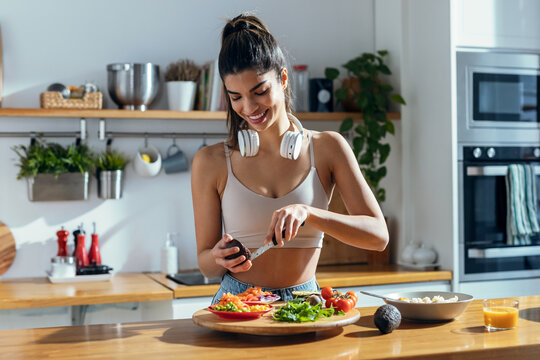 Fintess woman making a healthy poke bowl in the kitchen at home.
