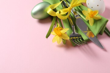 Cutlery set, Easter eggs and narcissuses on pale pink background, space for text. Festive table setting