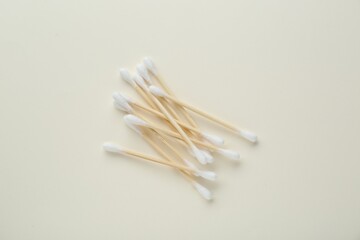 Heap of wooden cotton buds on beige background, flat lay