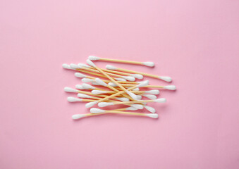 Heap of wooden cotton buds on pink background, flat lay