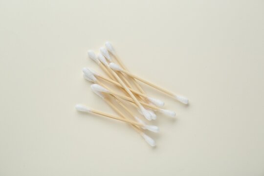 Heap of wooden cotton buds on beige background, flat lay