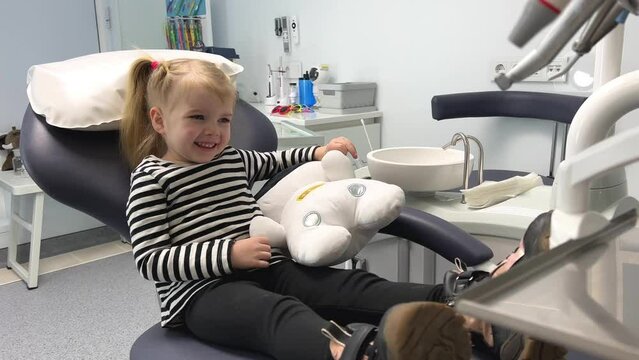 a little girl in a striped blouse in a dental office with a soft toy A sleepwalker or white astronaut laughs hugging waiting for a doctor no fear pediatric dentistry dentistry for children