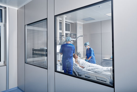 Two doctors attending woman patient in hospital ward. ICU