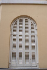 The old, ancient white wooden  window in a yellow facade. Texture. Background. close up. Detail.
