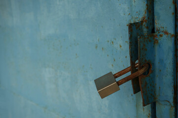 Large rusty padlock on the blue painted metal door. empty Copy space for text. Rusty lock hanging on rust-eaten gate  of the garage or barn. iron metal sheet.