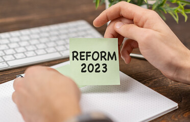 Reform 2023 Text on notebook in office desk workplace in hand businessman.