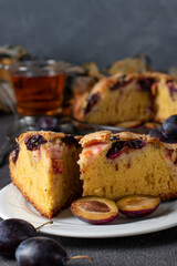 Homemade open pie with plums and cup of tea on gray background