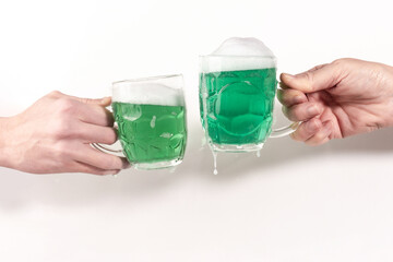 Freeze motion shot close-up view two glasses mugs of green beer dripping on white studio background