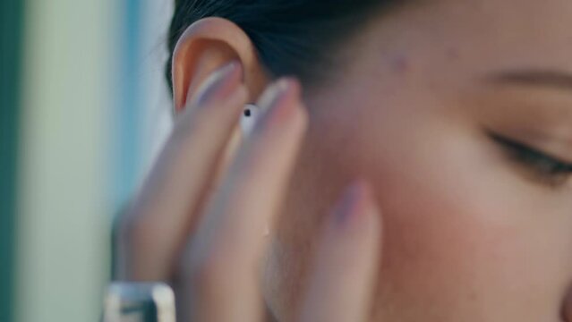 Closeup woman putting wireless earphone into ear. Girl wearing headset for music