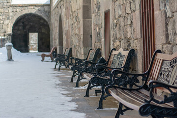 Fototapeta na wymiar Benches in the courtyard of the fortress. Walls of the old fortress and arch