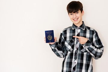 Young teenager boy holding Uruguay passport looking positive and happy standing and smiling with a confident smile against white background.