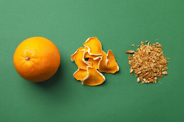 Dried orange zest seasoning, peel and fruit on green background, flat lay