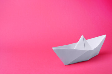 White paper boat on pink background, space for text. Origami art