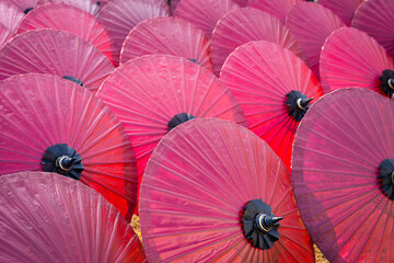 Beautiful red color of paper umbrella Traditional handmade umbrella a product that is unique and popular as a souvenir for tourists in travel of Chiang Mai, Northern Thailand.