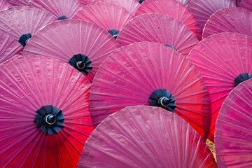 Beautiful red color of paper umbrella Traditional handmade umbrella a product that is unique and popular as a souvenir for tourists in travel of Chiang Mai, Northern Thailand.