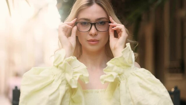 Portrait of pretty blond young woman with bad poor vision wearing glasses and looking around enjoying clear focus image of the surrounding world outdoors Eye care eyesight and vision concept