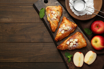Plakat Fresh tasty puff pastry with sugar powder, mint and apples served on wooden table, flat lay. Space for text