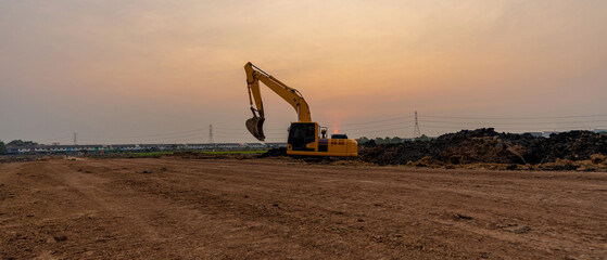 Excavator working on construction site at sunset background - obrazy, fototapety, plakaty
