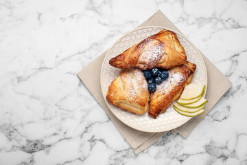 Fresh tasty puff pastry with sugar powder, pear and blueberries served on white marble table, top view. Space for text