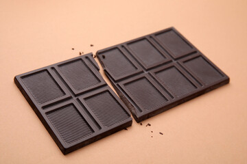 Broken tasty chocolate bar on brown background