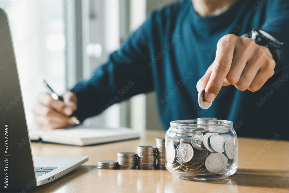 Wall mural hand putting coins in a piggy bank for save money and saving money concept.