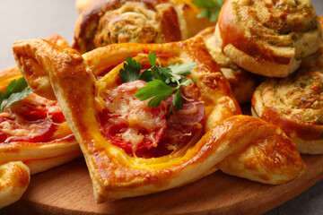 Different delicious puff pastry with tasty filling on wooden board, closeup