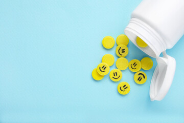 Yellow antidepressants with happy emoticons and medical bottle on light blue background, flat lay....
