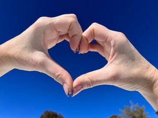 heart shaped hands against blue sky
