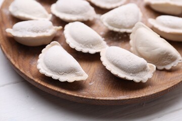 Fototapeta na wymiar Raw dumplings (varenyky) on wooden plate, closeup