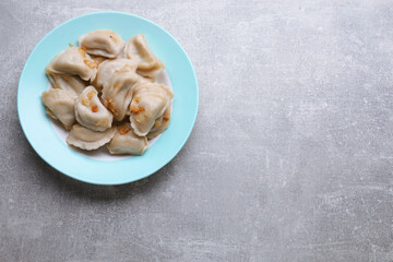 Delicious dumplings (varenyky) with potatoes and onion on grey table, top view. Space for text