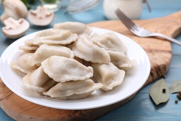 Fototapeta na wymiar Delicious dumplings (varenyky) with potatoes served on light blue wooden table, closeup