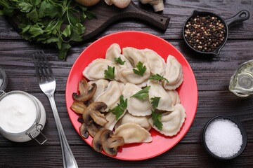 Delicious dumplings (varenyky) with potatoes, mushrooms and parsley served on brown wooden table,...