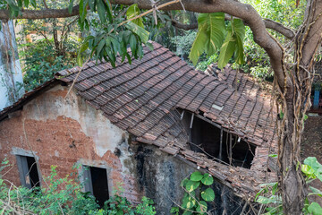 Top angle view of an old rustic dilapidated house with broken tiled roofs.