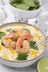 Tasty couscous with shrimps, bell pepper and basil on white textured table, closeup