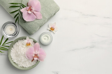 Fototapeta na wymiar Flat lay composition with different spa products and flowers on white marble table. Space for text