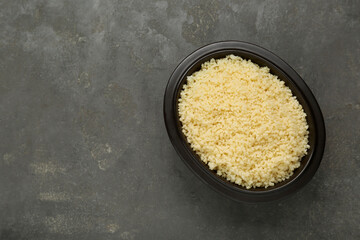 Bowl of tasty couscous on grey table, top view. Space for text