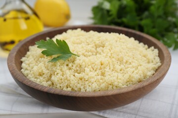 Tasty couscous with parsley on white table, closeup