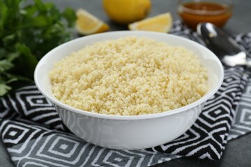 Bowl of tasty couscous on grey table, closeup