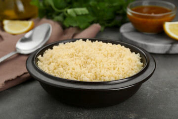 Bowl of tasty couscous on grey table, closeup