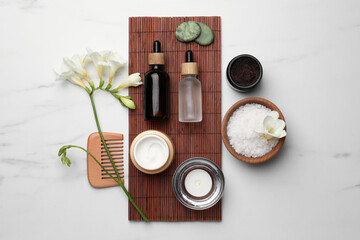 Fototapeta na wymiar Flat lay composition with different spa products and flowers on white marble table