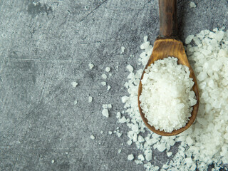 Fototapeta na wymiar sea salt, a pile of sea salt in a wooden spoon on a dark stone background close-up